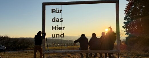 Foto mit Plakatrahmen aus Holz und Sitzbank in der Natur mit Sonnenuntergang und Menschen