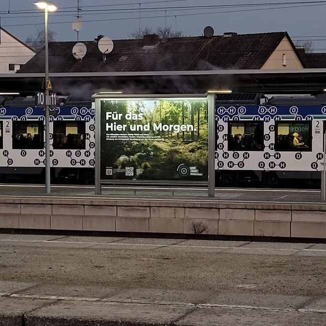 Foto mit Plakat an einem Bahnhof